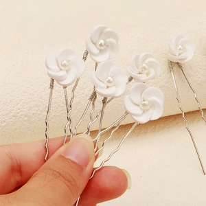 Close-up of white clay flower hair pins with pearls and silver U-shaped metal clips