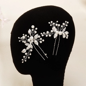 Detail of two handmade bridal hair pins with white pearls and silver leaf accents