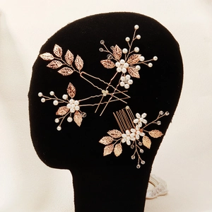 Detail view of gold leaf and pearl bridal hair comb set on black velvet stand