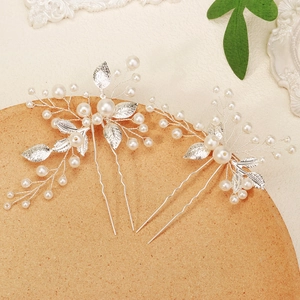 Detailed close-up of handmade silver leaf hair pins with white pearls for bridal hairstyles