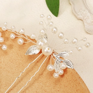 Macro view of handmade bridal hair pin with silver leaves and pearls on wood base