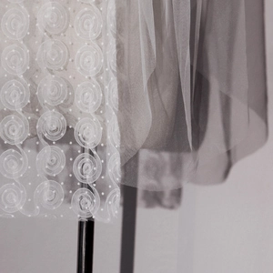 Detail of bridal veil featuring 3D rose lace embroidery and delicate white polka dot mesh