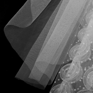 Close-up of elegant white lace wedding veil with floral embroidery and mesh texture