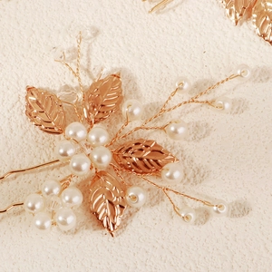 Macro shot of gold leaf hairpin with pearls and intricate beads for vintage bridal styling