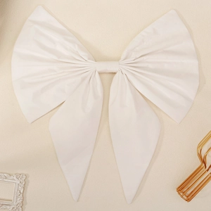 Detail of a large white bridal bow made of matte fabric on a decorative beige background