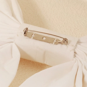 Elegant white fabric bridal bow accessory with metal safety pin brooch back for wedding gowns