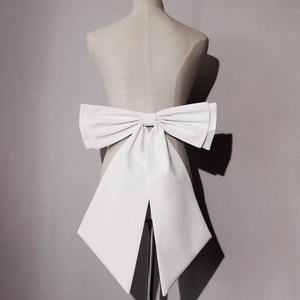Detail of multi-layered white satin bridal bow with long ribbons on a formal gown