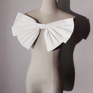 Detailed close-up of a large white 3D bow accessory on a bridal gown mannequin
