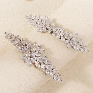 Elegant silver hair clips with leaf-shaped sparkling zircons on a beige textured background