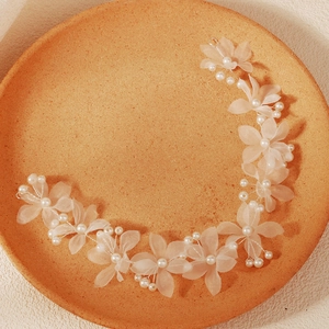 Accessoire cheveux de mariée en tulle et perles sur un plateau décoratif orange