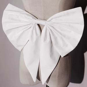 Macro detail of large white fabric bow decoration for kids princess dress back waist