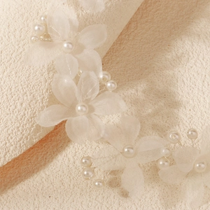 Détail macro du bandeau de mariée avec pétales de tulle translucides et grappes de perles