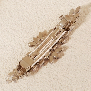 Close-up of silver metal spring hair clip back showing detailed hinge and crystal setting