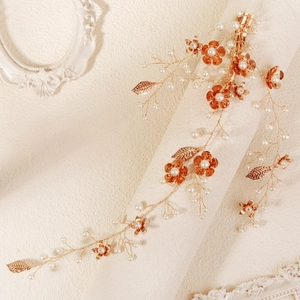 Detail van bruidshaarstuk met roségouden bladeren en witte parels aan zachte ketting