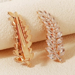 Detail of leaf-shaped gold hair clips with sparkling zircons and duckbill clasp design