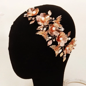 Dettaglio di un fermaglio sposa in oro rosa con fiori metallici, perle e strass