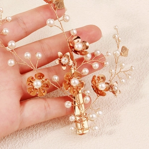 Detail van handgemaakte gouden bruidshaarspeld met witte parels en bloemmotieven