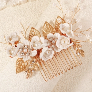 Detail van gouden haarkam met witte zijden bloemen en parels voor de bruid