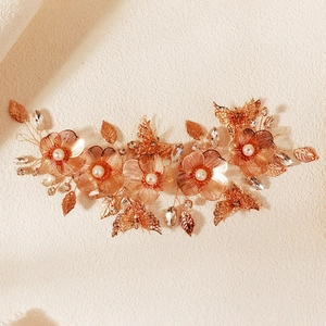 Dettaglio macro dell'accessorio sposa in oro rosa fatto a mano con perle e petali in metallo