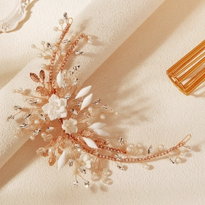 Macro detail of handmade bridal headband with gold leaves, white flowers and pearls