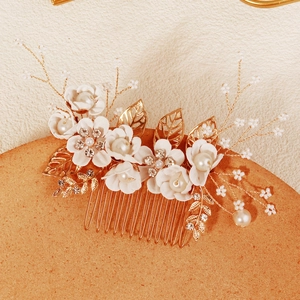 Detail van gouden haarkam met witte bloemen en parels voor bruidskapsels en bruiloften