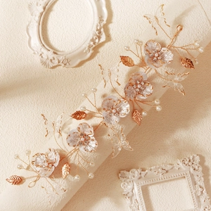Detailed macro of wedding headband with beaded resin flowers, gold leaves and pearls
