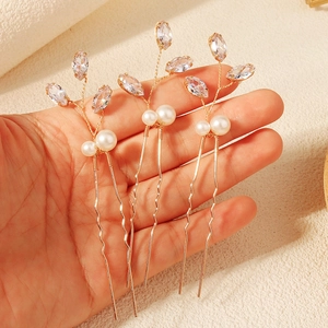 Dettaglio di tre forcine da sposa con filo dorato, cristalli e perle bianche