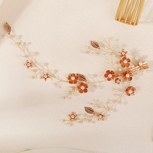 Bruids haarrank in champagne goud met parels en oranje bloemen voor bruidskapsels
