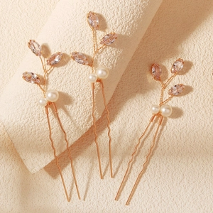 Dettaglio di tre forcine dorate per sposa con cristalli rosa e perle a forma di ramo