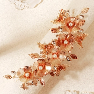 Dettaglio della fascia da sposa in oro rosa con fiori di metallo, perle e cristalli
