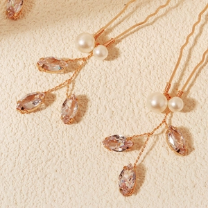 Dettaglio di forcine da sposa dorate con perle bianche e strass a forma di marquise