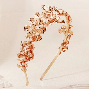 Détail de pétales en métal or rose et perles blanches sur un serre-tête mariée