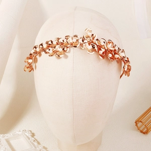 Détails d'un bandeau de mariée avec fleurs métalliques dorées et perles blanches