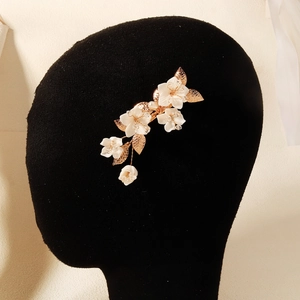 Detailed side view of golden flower hair clip with white resin petals and pearl centers
