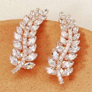 Elegant gold leaf earrings with marquise cubic zirconia on a rustic cork surface