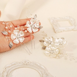 Detailed close-up of bridal hair pins set with white silk flowers and pearls