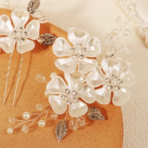 Close-up of bridal hair pin with white acrylic flowers, pearls and crystal details