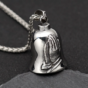 Vintage stainless steel guardian bell necklace with prayer hands on textured rock