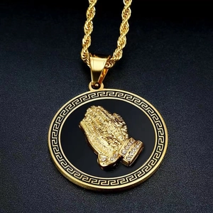 Détail macro du pendentif mains en prière plaqué or hip-hop avec accents diamantés