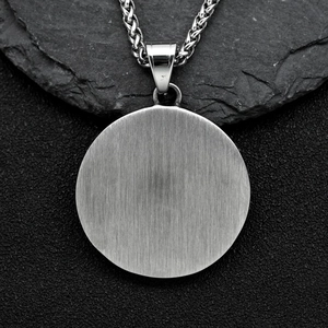 Polished stainless steel evil eye pendant necklace with braided chain on dark rock
