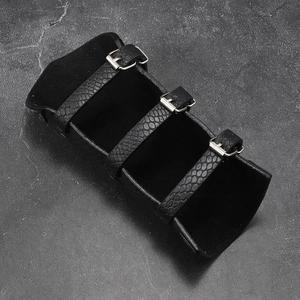 Detail of medieval black leather arm guard featuring scale texture and adjustable buckles