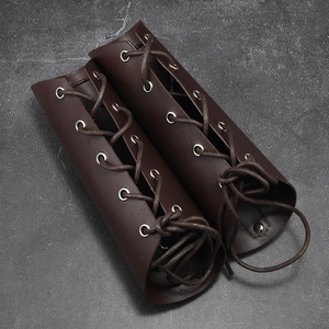 Pair of vintage brown leather arm guards with adjustable crisscross lacing and metal rivets