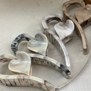 Detail view of large marble ink pattern heart hair claws on a stone tray
