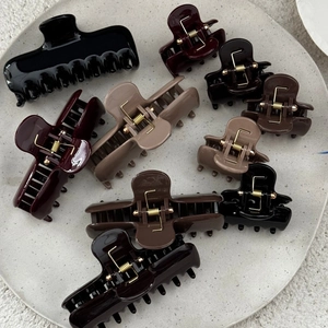 Solid color thick hair claw clips in various sizes and earthy tones on a round stone tray