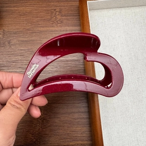 Elegant heart-shaped burgundy acetate hair claw clip with glossy finish and logo