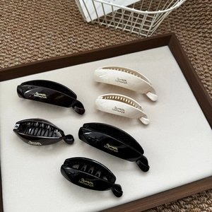 Close-up of gloss banana clips in black, cream and brown on a wooden display tray