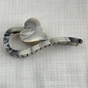 Detailed close-up of a large heart-shaped hair claw with grey marble ink pattern texture