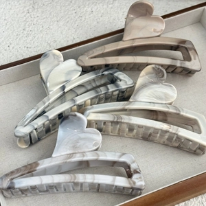 Detail showing marble texture acetate heart hair claw clips in four neutral colors