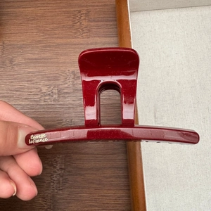 Detail view of burgundy glossy hair claw with elegant golden Barrette La France text