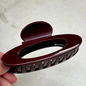 Close-up of burgundy high-gloss shark hair clip with secure spring and gold-plated bead detail